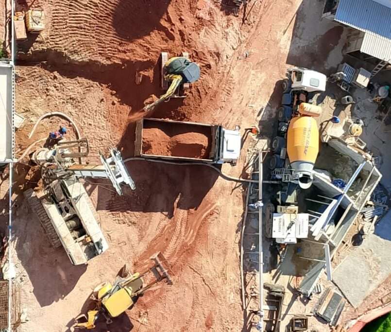 Processo de perfuração de estacas profundas da fundação com uso de máquina perfuratriz tipo hélice, concretagem das estacas com betoneira, carregamento de terra e arrasamento de estacas.